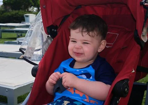 Cute boy sitting in his stroller by the pool at the resort Stock Photos