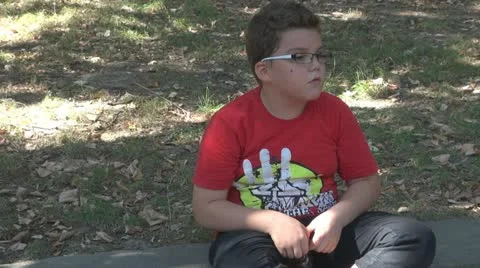 Cute boy sitting in park thinker Vídeos de archivo 11953904
