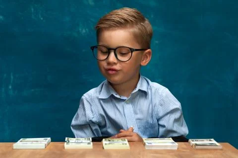 Cute boy sitting at the table and counting money Stock Photos