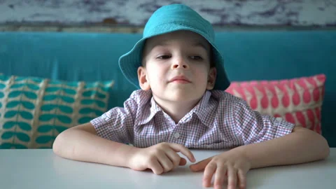 Cute boy is sitting at a table in cafe and waiting for food Video stock 107145800