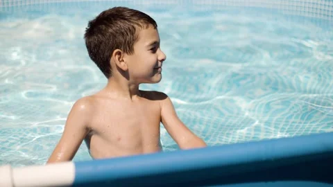 Cute boy smiling and having fun swimming in backyard pool on sunny summer day Stock Footage 342377781