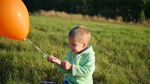 Cute boy standing with balloons in field Vídeo Stock 80046799