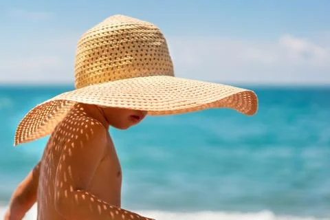 Cute boy in a straw hat on the beach Stock Photos