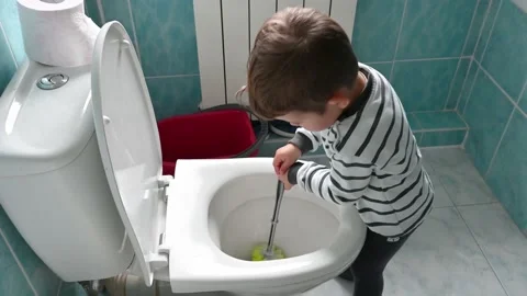 Cute boy in striped clothes washes a toilet. The child cleans at home. Stock Footage 171381210