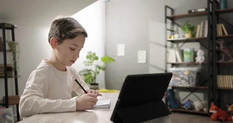Cute boy studying online from home talking with tutor teacher by video call on Stock Footage 262194364