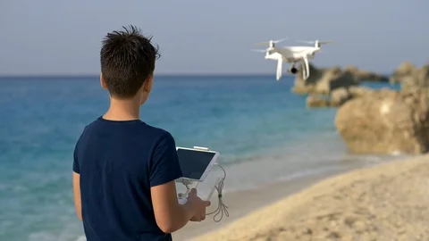 Cute boy studying operate drone with remote control at empty beach sea shore Stock Footage 97933144