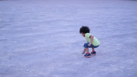 Cute boy throwing small stone at the top of a mountain he is wearing yellow  Stock Footage 159662122
