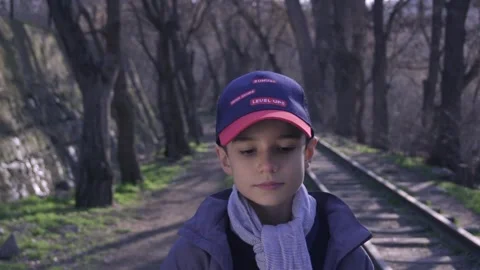 Cute boy walking on railway in forest with a book in his hand 库存影片 172584825