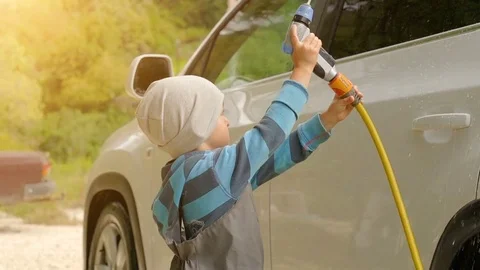Cute boy washing a car with hose Stock Footage 80727090