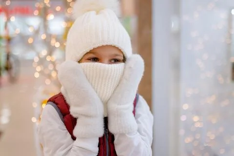 Cute boy in white bobble hat and scarf at mall near showcase. blurred bright Stock Photos