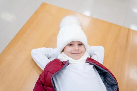 Cute boy in a white fluffy hat in a shopping center against the background of Stock Photos