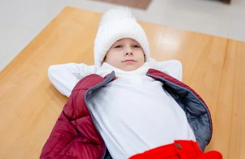 Cute boy in a white fluffy hat in a shopping center against the background of Stock Photos