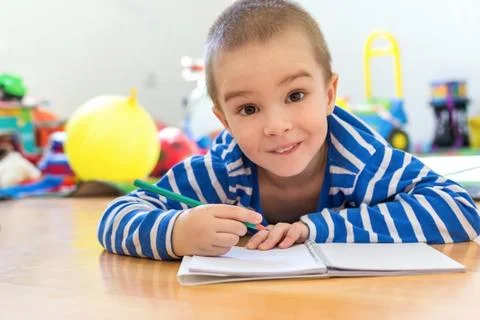 Cute boy writing something in notebook on the floor Stock Photos
