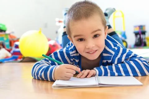 Cute boy writing something in notebook on the floor Stock Photos