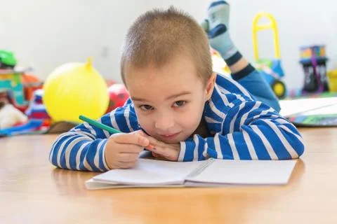 Cute boy writing something in notebook on the floor Stock Photos
