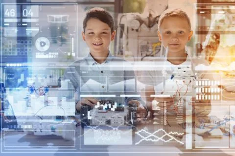 Cute boys smiling while sitting together and working at their project Stock Photos