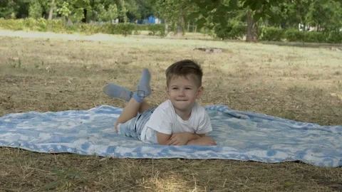Cute, brooding baby lying on a blanket on his stomach in the Park at sunset  스톡 동영상 113603459