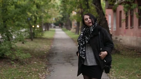 Cute brunette in a black coat, posing on a city street Stock Footage