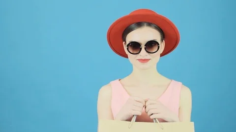 Cute Brunette in Red Hat and Cool Sunglasses is Holding Shopping Bag in Hands Видео 75239331
