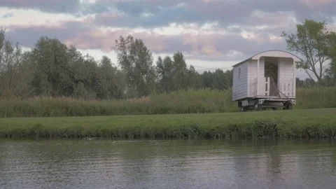Cute cabin, caravan on the side of a river by the water in peaceful landscape Stock Footage 234796678