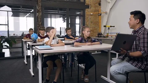 Cute caucasian boy sitting behind desk together with classmate, raising hand and Stock Footage 114976487