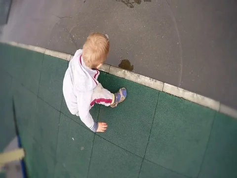 Cute caucasian child baby kid boy is plays a toy in dirty puddle after a rain Stock Footage