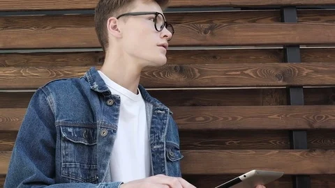 Cute caucasian man working on tablet computer by the street Video stock 77395921