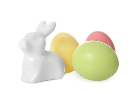Cute ceramic Easter bunny and dyed eggs on white background Foto stock