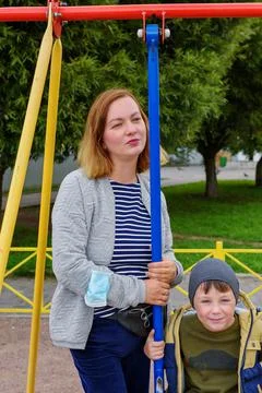 Cute charming boy of five years old, swinging on an outdoor playground Stock Photos