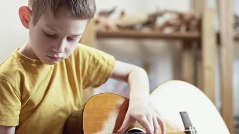 A cute cheerful boy is playing classical guitar in the children's room. Stock Footage 277942836