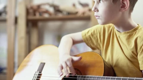 A cute cheerful boy is playing classical guitar in the children's room. Stock Footage 277942837