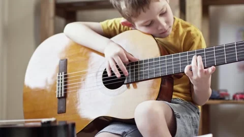 A cute cheerful boy is playing classical guitar in the children's room. Stock Footage 277942852