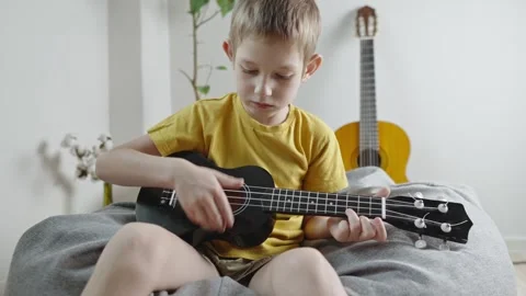 A cute cheerful boy is playing the ukulele in the children's room.  Stock Footage 282255308