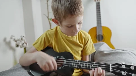 A cute cheerful boy is playing the ukulele in the children's room.  Stock Footage 282255366