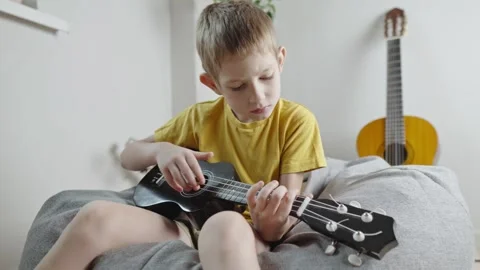 A cute cheerful boy is playing the ukulele in the children's room.  Stock Footage 282255372