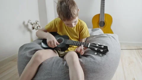 A cute cheerful boy is playing the ukulele in the children's room.  Stock Footage 282255446