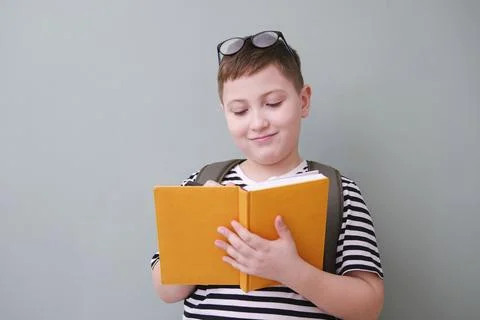 A cute cheerful boy in stripped tee shirt in glasses and is writing a yellow  Stock Photos