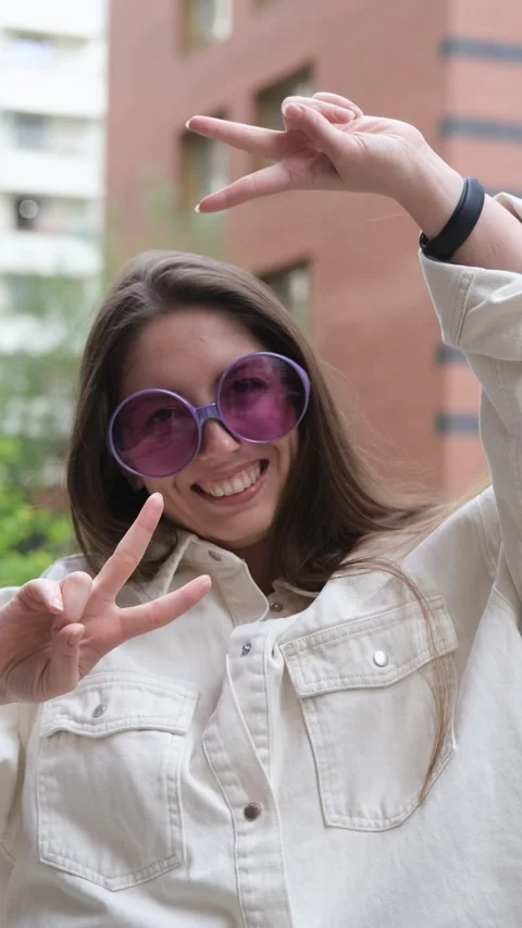 Cute cheerful charming girl poses for camera in summer on city street, hands and Video stock 316862053