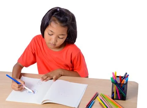 Cute cheerful child drawing using color pencil while sitting at table isolate Stock Photos