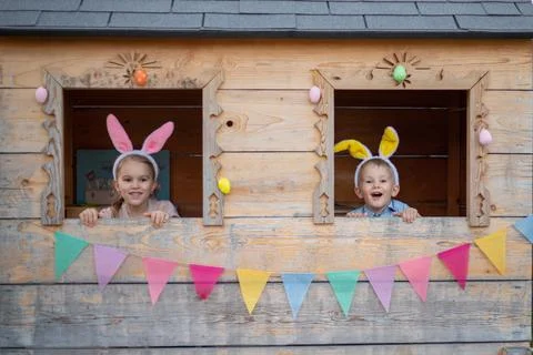 Cute cheerful kids in bunny ears in the playhouse celebrate easter. brother and Stock Photos