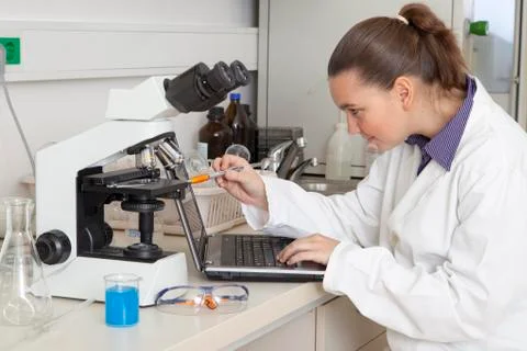 Cute chemist in modern laboratory using notebook Stock Photos