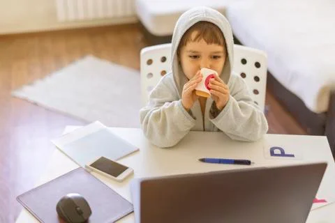A cute child in a bathrobe is studying at the computer online early in the Foto stock