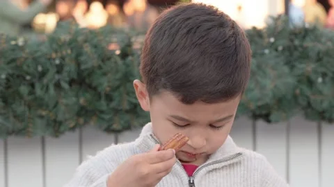 A cute child bites a churros with chocolate sauce on a faire Stock Footage 244635473