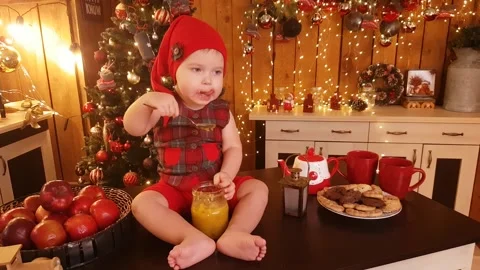 Cute child boy with bare feet, sits on the table and eats jam Stock Footage 234125243