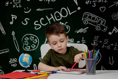 Cute child boy doing homework. Clever kid drawing at desk. Schoolboy. Element Stock Photos