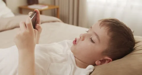 Cute child boy School Boy holds a phone, kid using smartphone, child browsing Stock Footage 237183405