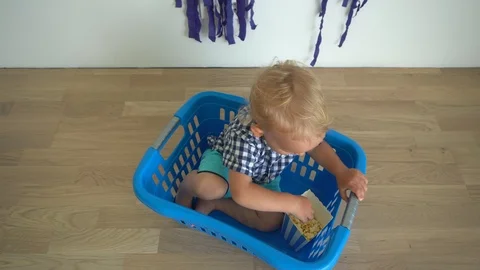 Cute child boy sitting in laundry box and eating popcorn. Gimbal motion top view Stock Footage 115129585