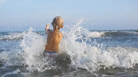 A cute child breaking sea waves and splashing in water in slow motion 50fps Stock Footage 50148149