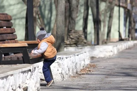 Cute child climbing on the bench in the spring park Fotos de archivo