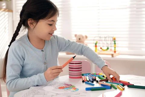 Cute child coloring drawing at table in room Foto stock